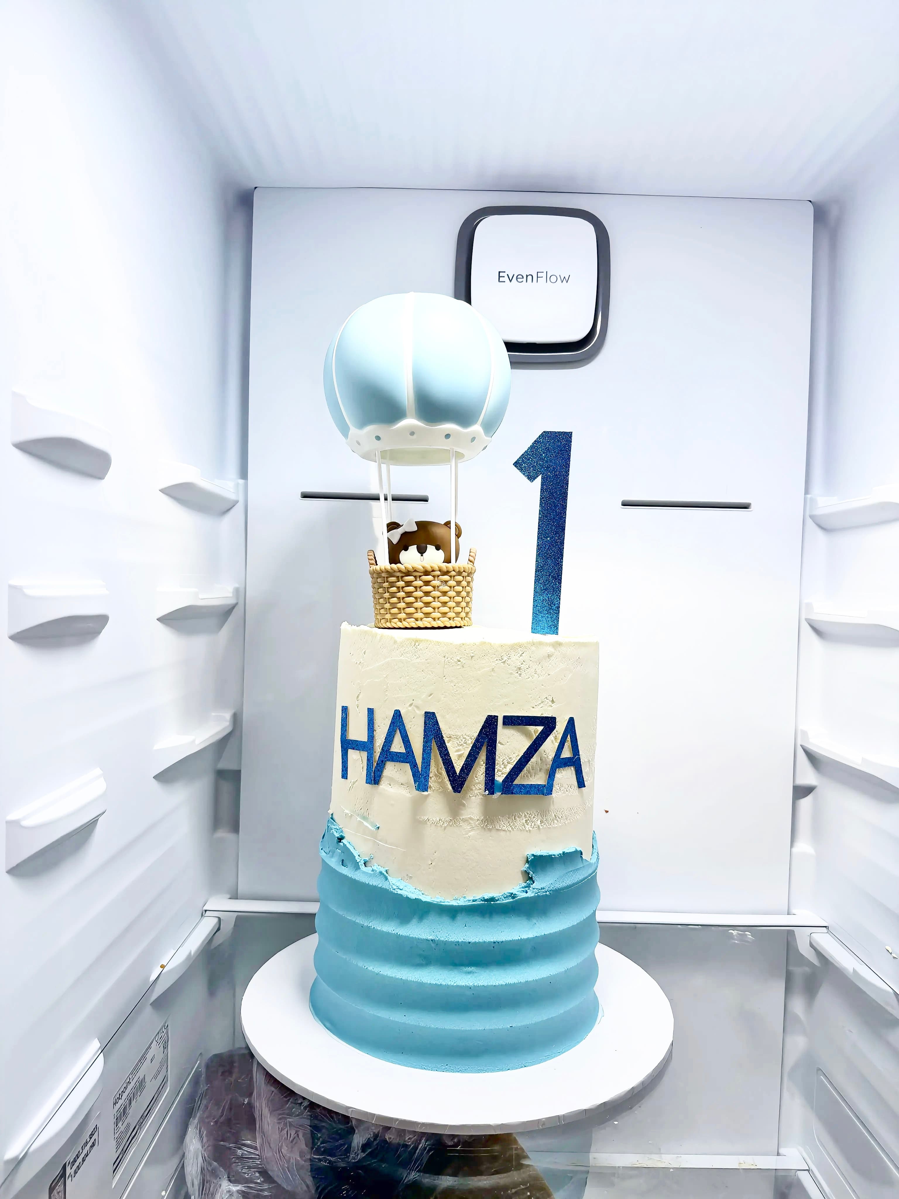 Blue first birthday cake with hot-air balloon topper